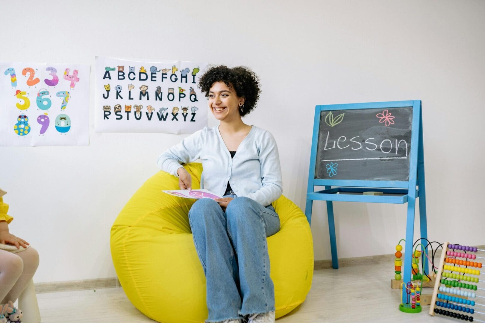 A woman sitting on a bean bag chair in front of a chalkboard.